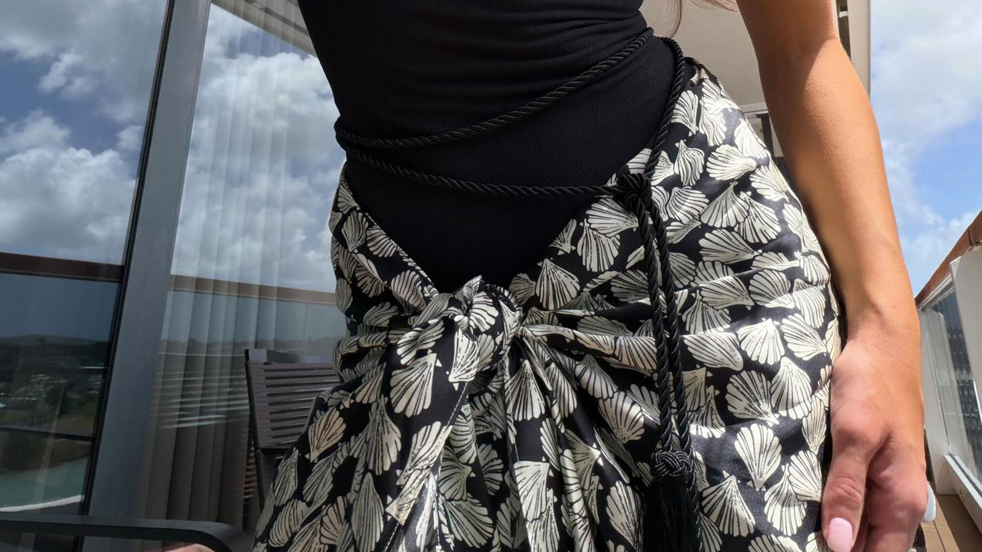 @emmaleger selfie wearing a black strapless swimsuit and printed pareo