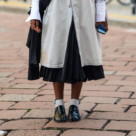 woman wearing skirt, coat, loafers, and socks 