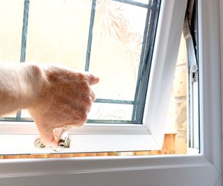 Hand opening a white uPVC bathroom window