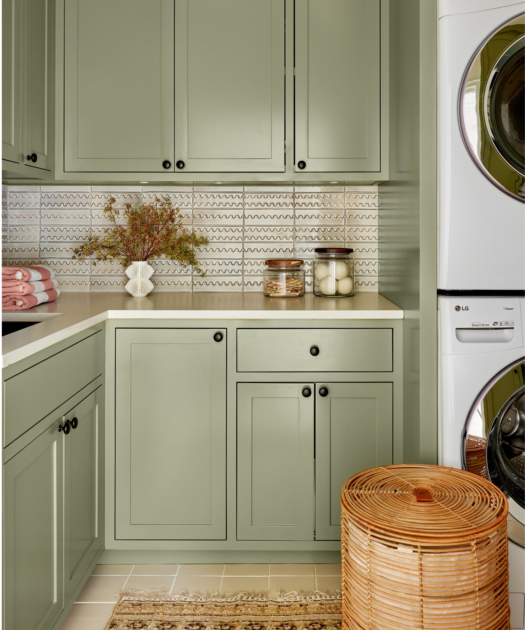 Laundry room with green cabinets, tiled floor, rattan baskets