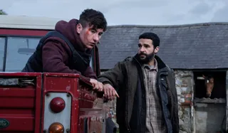 barry keoghan sits on a red truck while christopher abbott stands next to it in a still from the movie bring them down