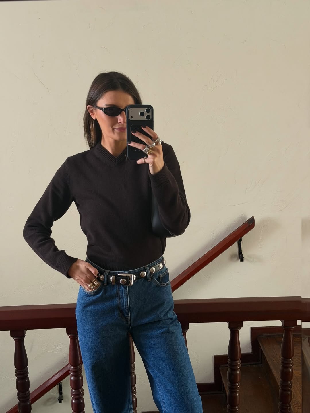Woman in high v-neck brown sweater and jeans.