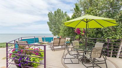 Raised patio with table and chairs and green patio umbrella