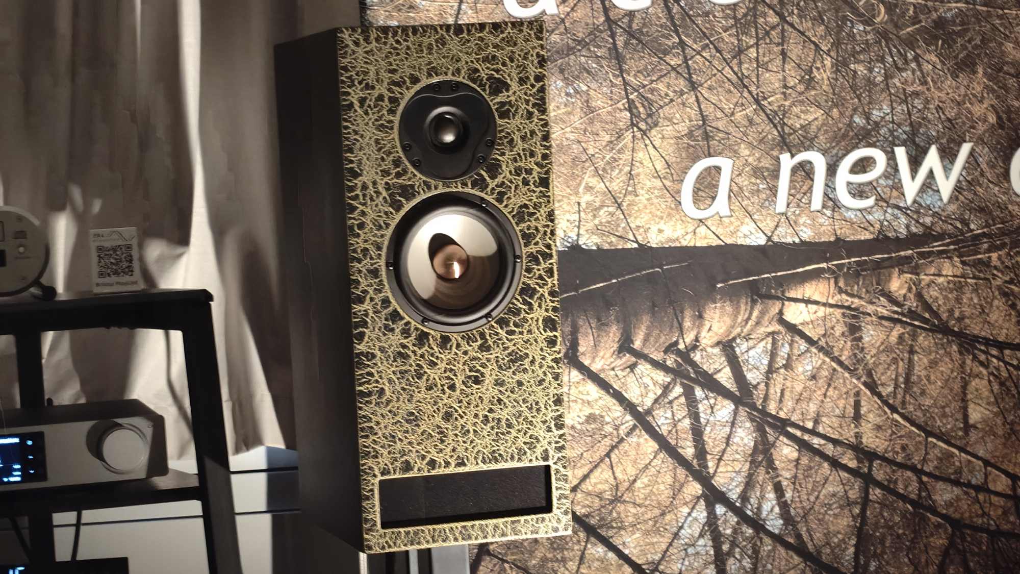 A Era Acoustics XTL next to a tree background.