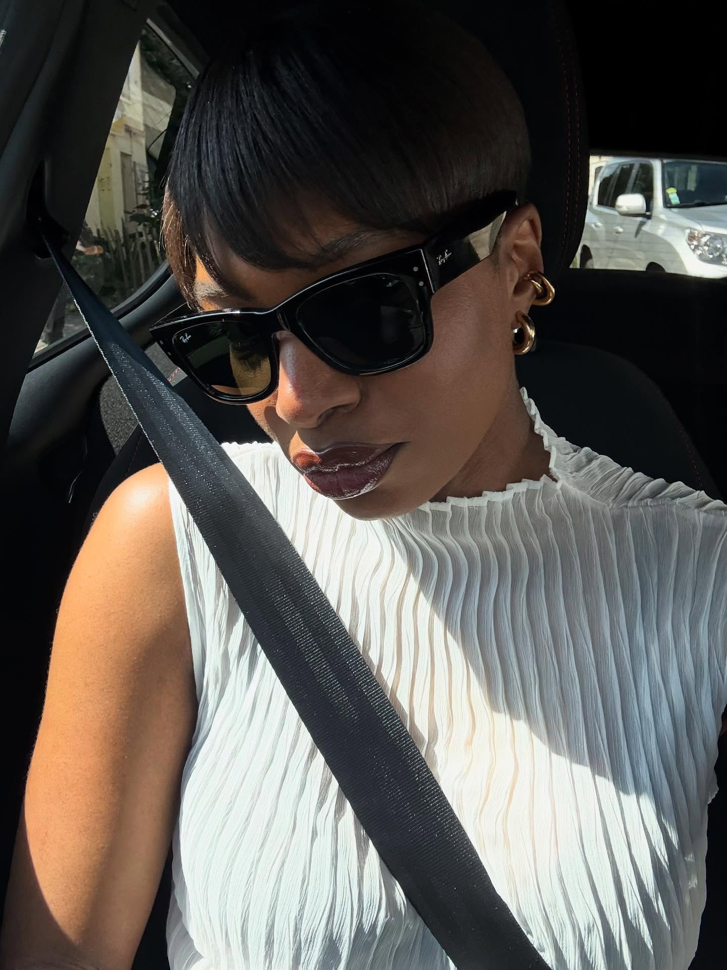 A woman wearing sunglasses in a car with sweeping bob hairstyle