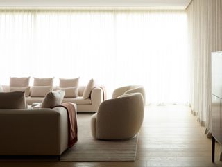 A living room bathed in natural light, with two sets of sofas in neutral tones