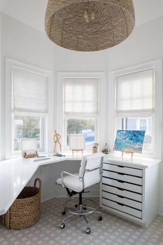 home office in white - walls, desk and white chair in front of corner windows
