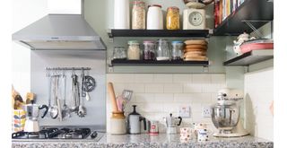 Kitchen countertop beside the oven showing a stand mixer below shelves of cookbooks and baking tools to show a rule for organizing kitchen countertops with thoughtfulness