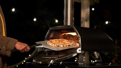 cooking pizza at nighttime in winter in an oven by Ooni