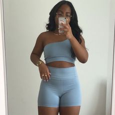 Kaitlin wears blue workout short set and gold jewlery while taking a mirror selfe