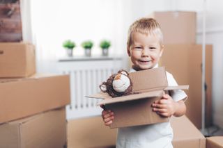Cute toddler helping out packing boxes and moving