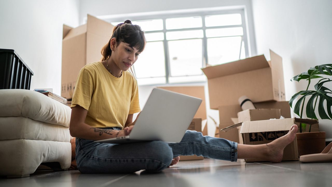 A young woman sits on the floor with moving boxes.