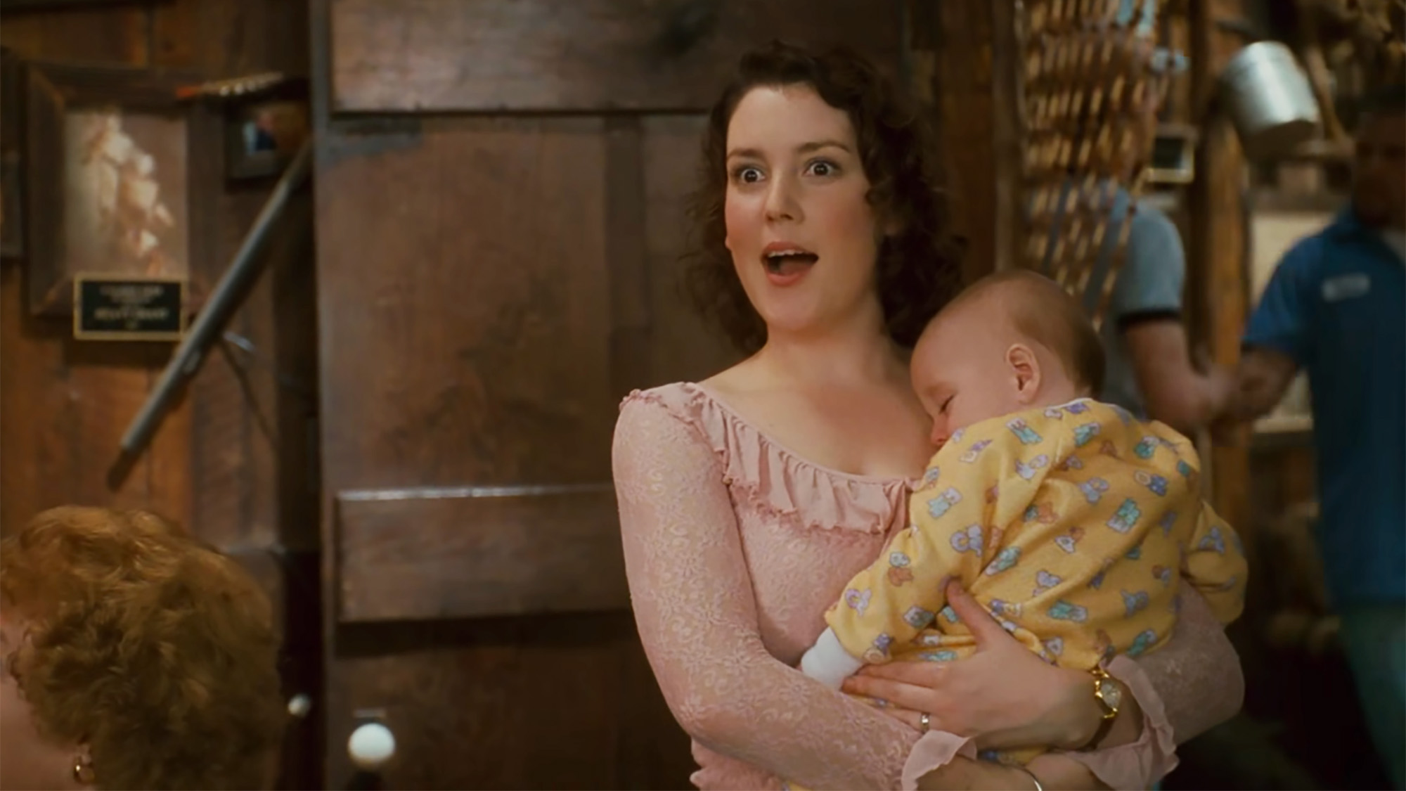 Melanie Lynskey looks surprised while holding a baby in a bar in Sweet Home Alabama.