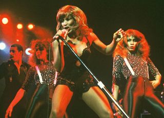 Photo of Tina Turner, Tina Turner performing on stage with dancers in 1979.