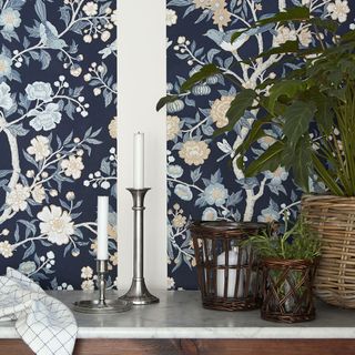 printed wallpaper on wall with candlestick and potted plants