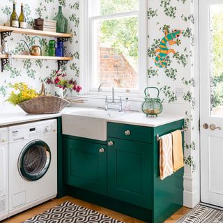 washing machine in utility room with botanical wallpaper and green cabinetry