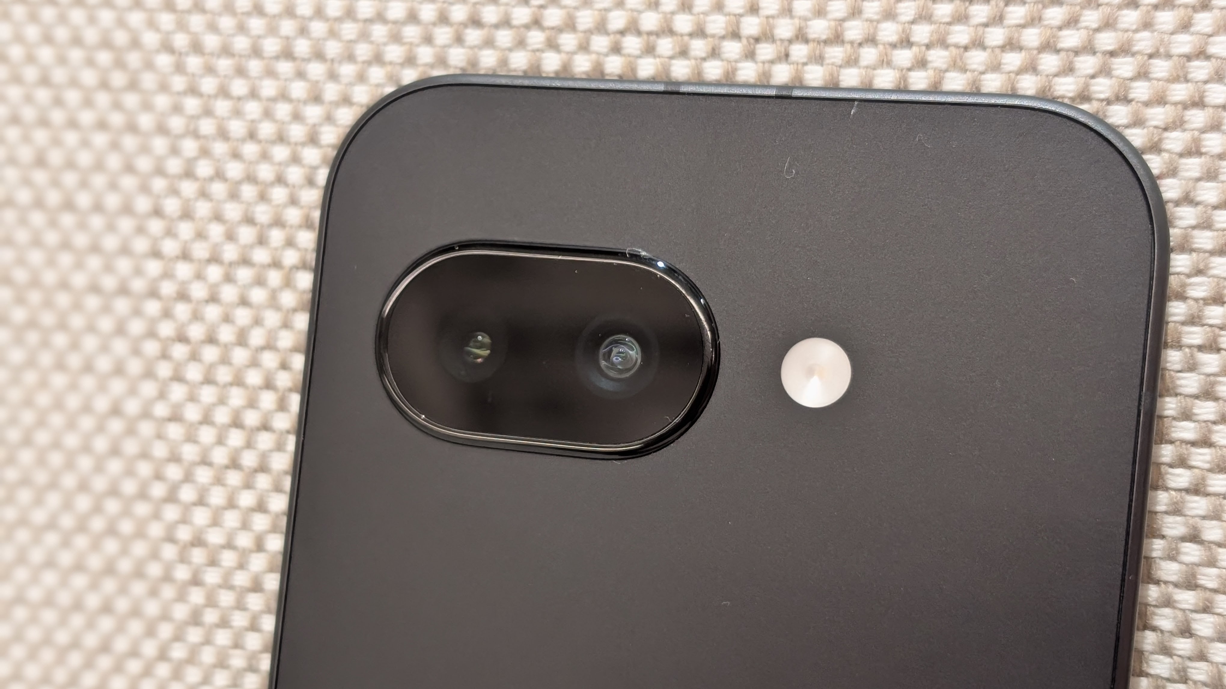 A close-up of the Obsidian Google Pixel 9a, the photos focused on the camera cutout and LED.