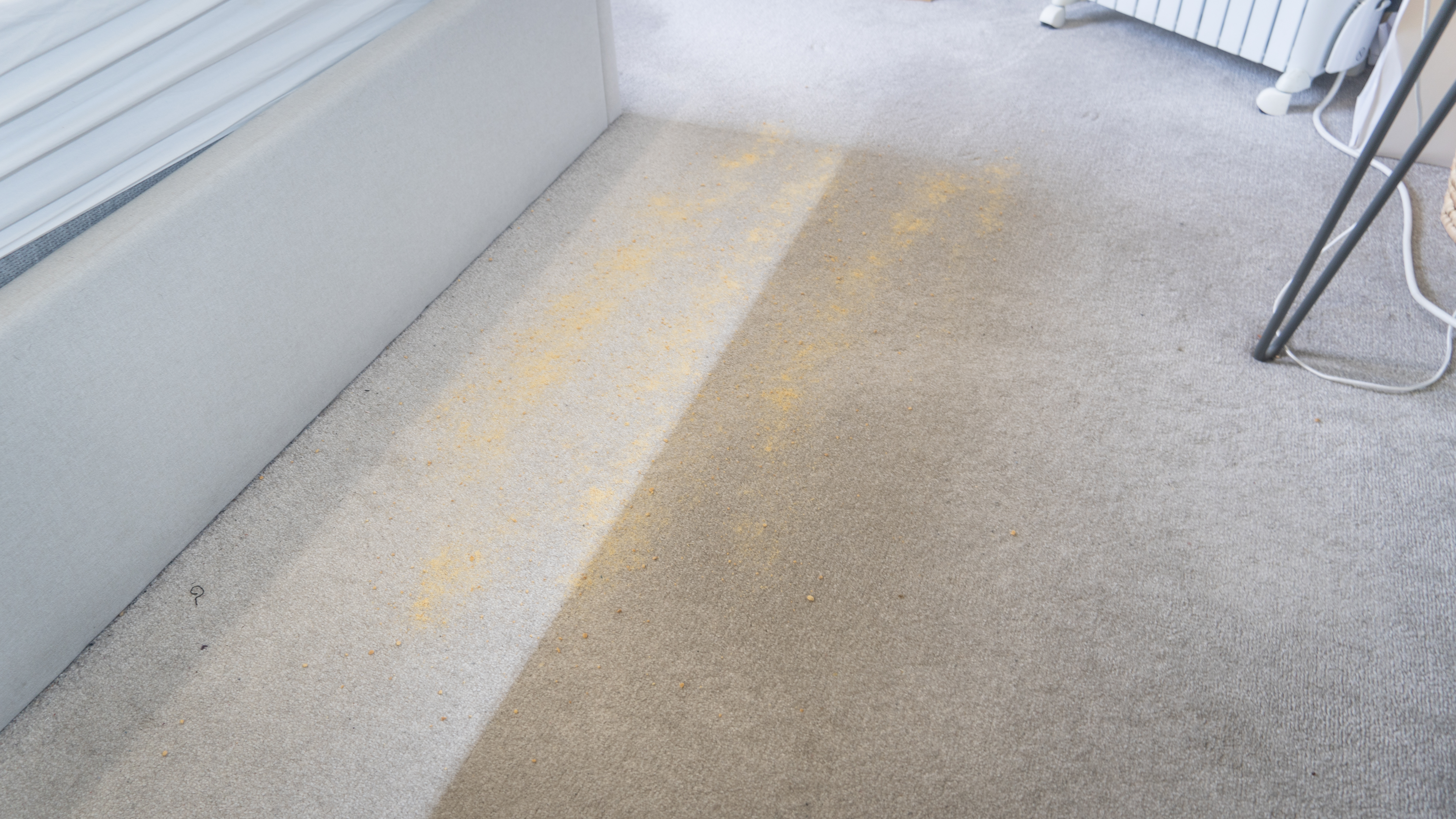 Crumb mix sprinkled on carpet in front of Eufy E20, ready for suction test