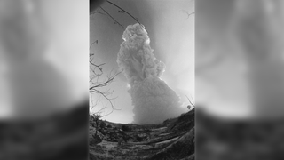 a large cloud of ash and smoke rises into the air above a desert landscape