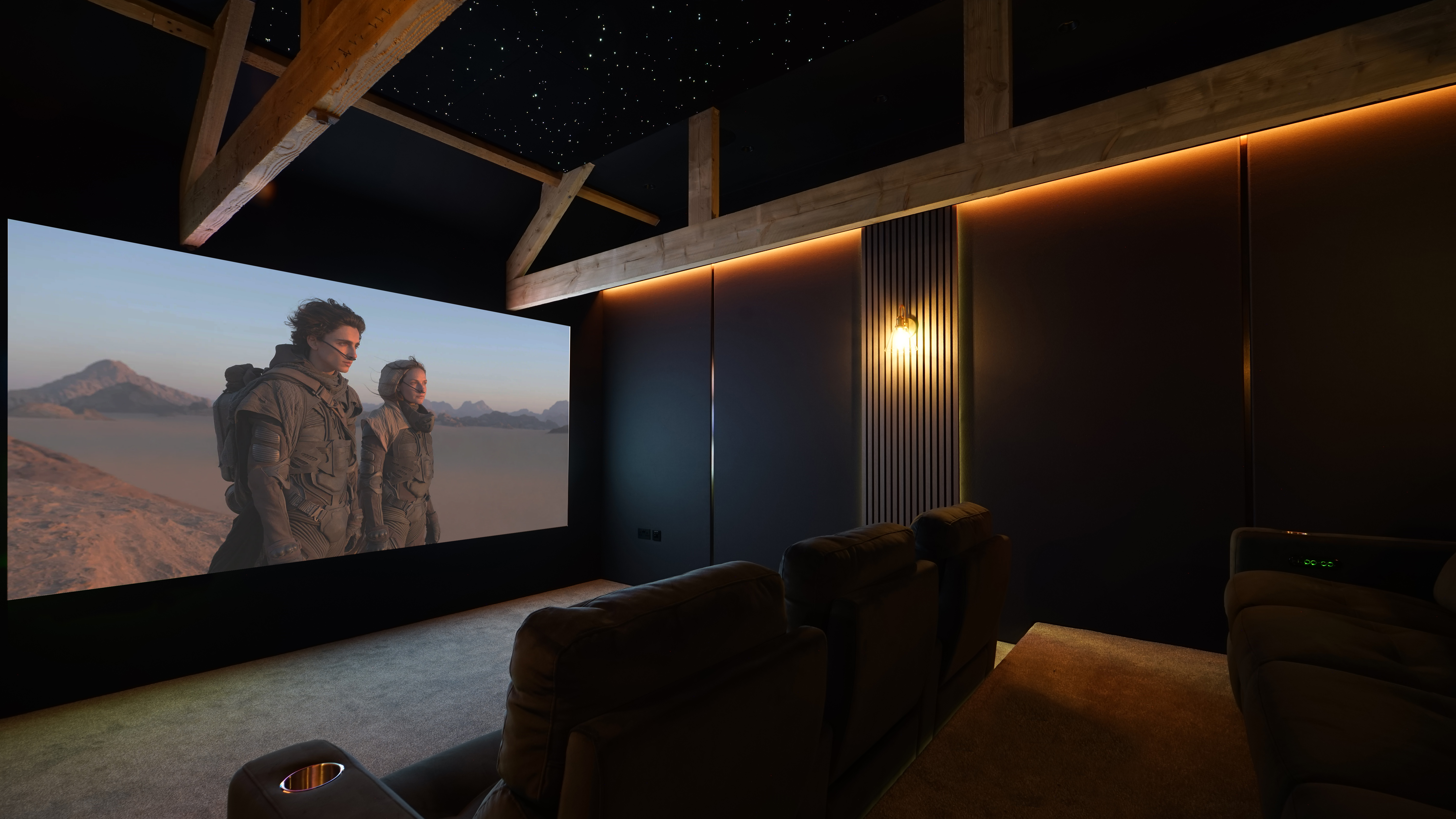 Home theater space with seating and screen showing image from Dune 2