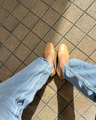 Woman wearing light wash jeans with nude ballet flats.