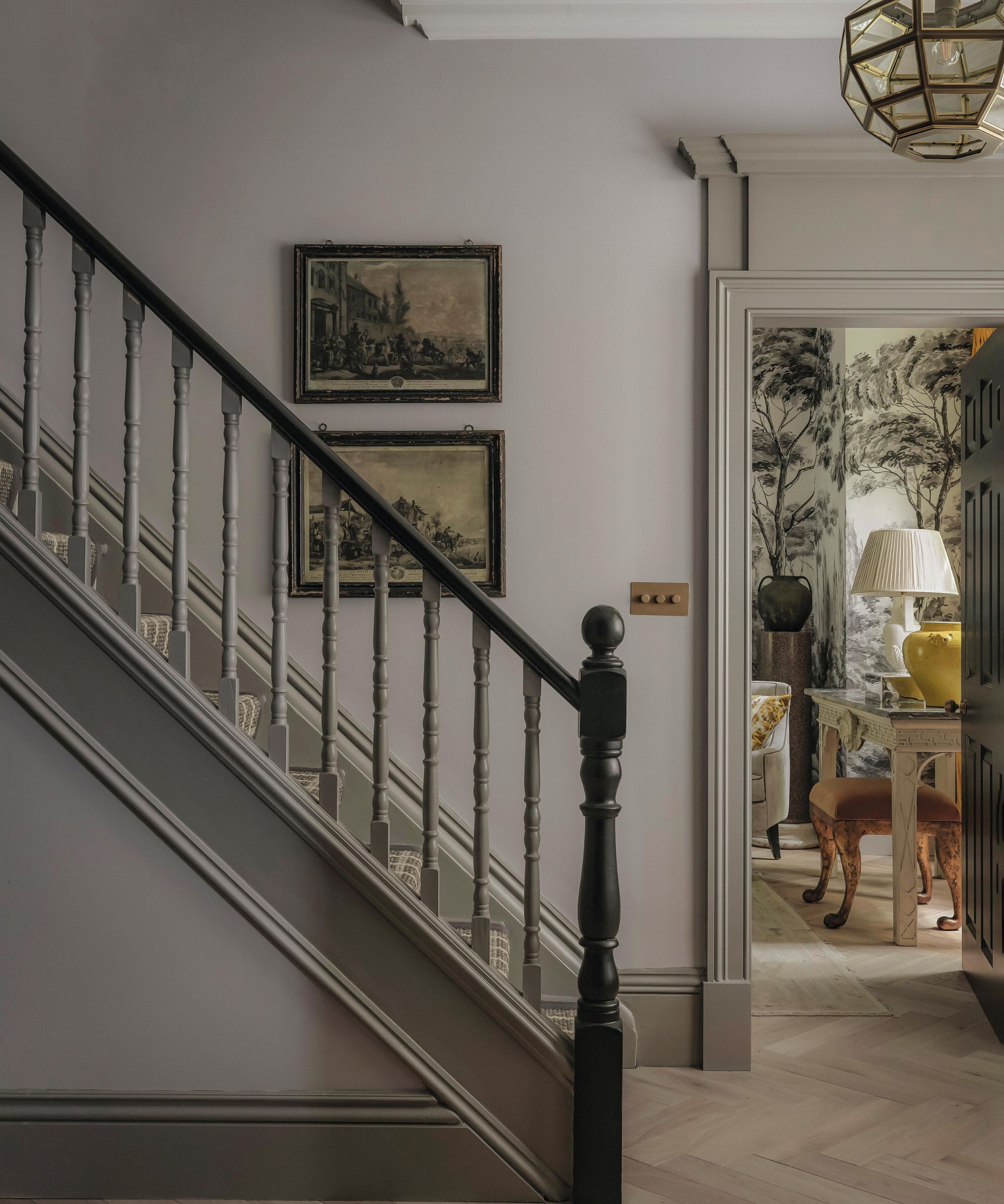 a grand london hallway painted in a soft lavender hue with door moldings into a sitting room with mural wallpaper