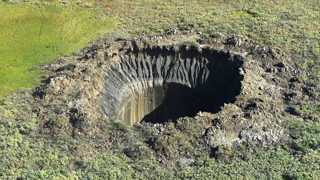 a deep crater in a grassy field