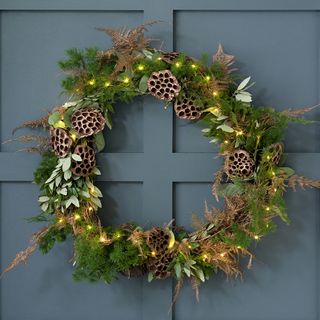 Green plant circled wreath decorated with fairy lights and dried flowers