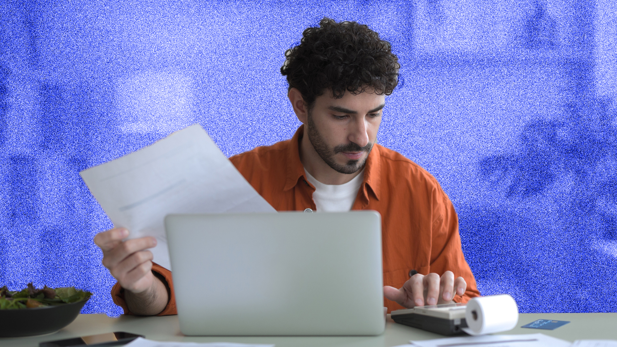 Front view of a young man checking bills in his apartment.