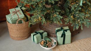 A close-up of the bottom of the Christmas tree with green wrapped gifts and a bowl of baubles