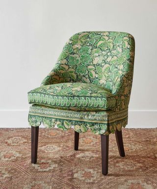Green pattern chair with scalloped skirt edge on wooden floors with plain white walls