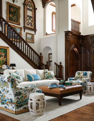 library seating space with chinoiserie chairs leather ottoman and dark wood stairs in background