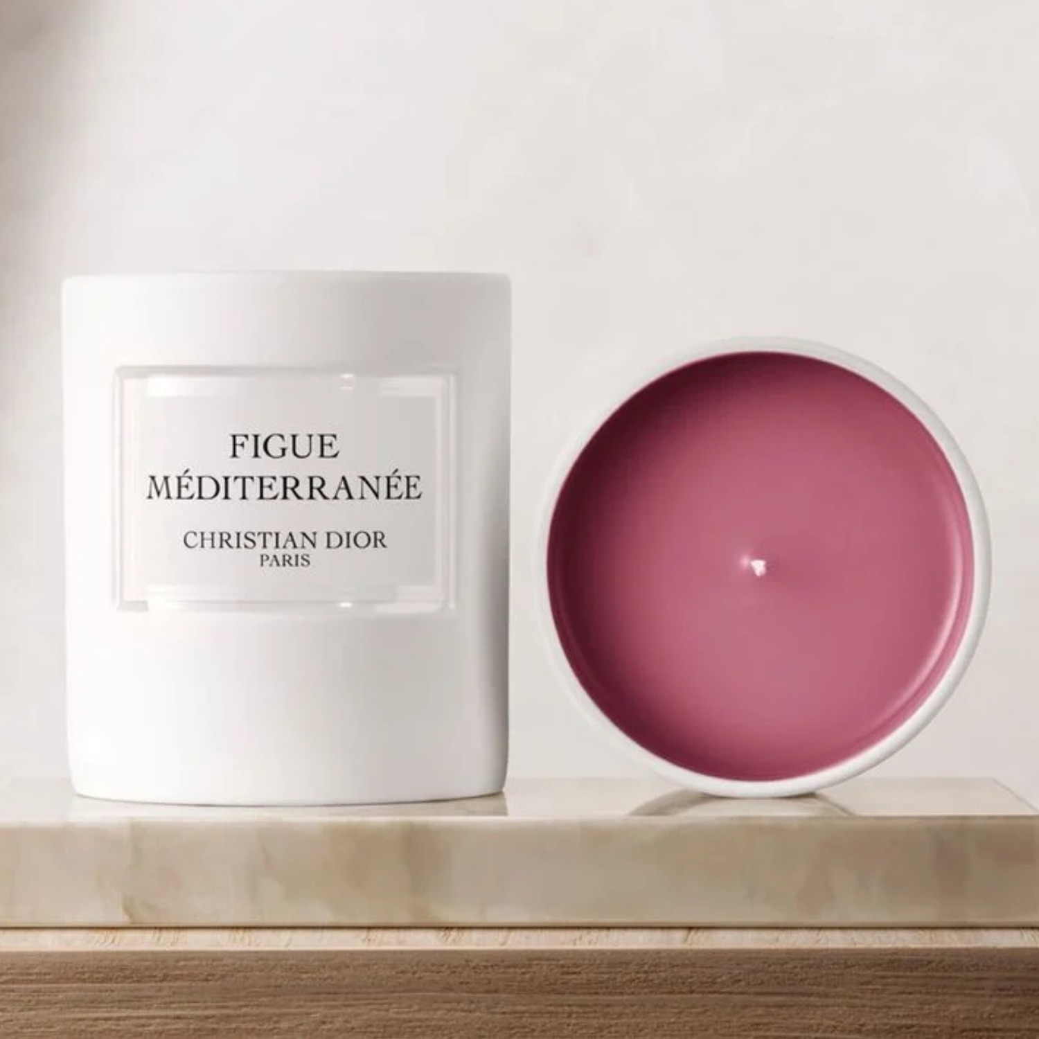 A ceramic candle with pink wax on a marble tablet