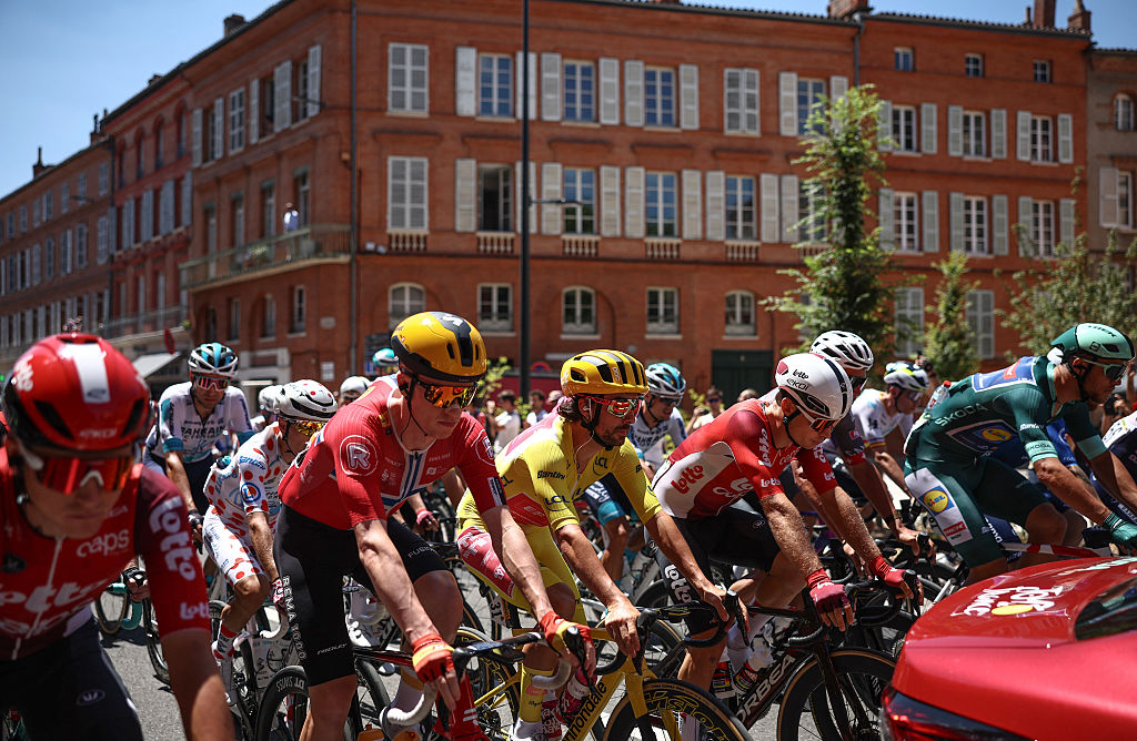 Uno-X Mobility team's Norwegian rider Andreas Leknessund (2nd L), EF Education - EasyPost team's Irish rider Ben Healy wearing the overall leader's yellow jersey (C), and Lidl - Trek team's Italian rider Jonathan Milan wearing the best sprinter's green jersey (R) cycle in a procession behind the race direction vehicle in central Toulouse during the 11th stage of the 112th edition of the Tour de France cycling race, 156.8 km starting and finishing in Toulouse, southwestern France, on July 16, 2025. (Photo by Anne-Christine POUJOULAT / AFP)