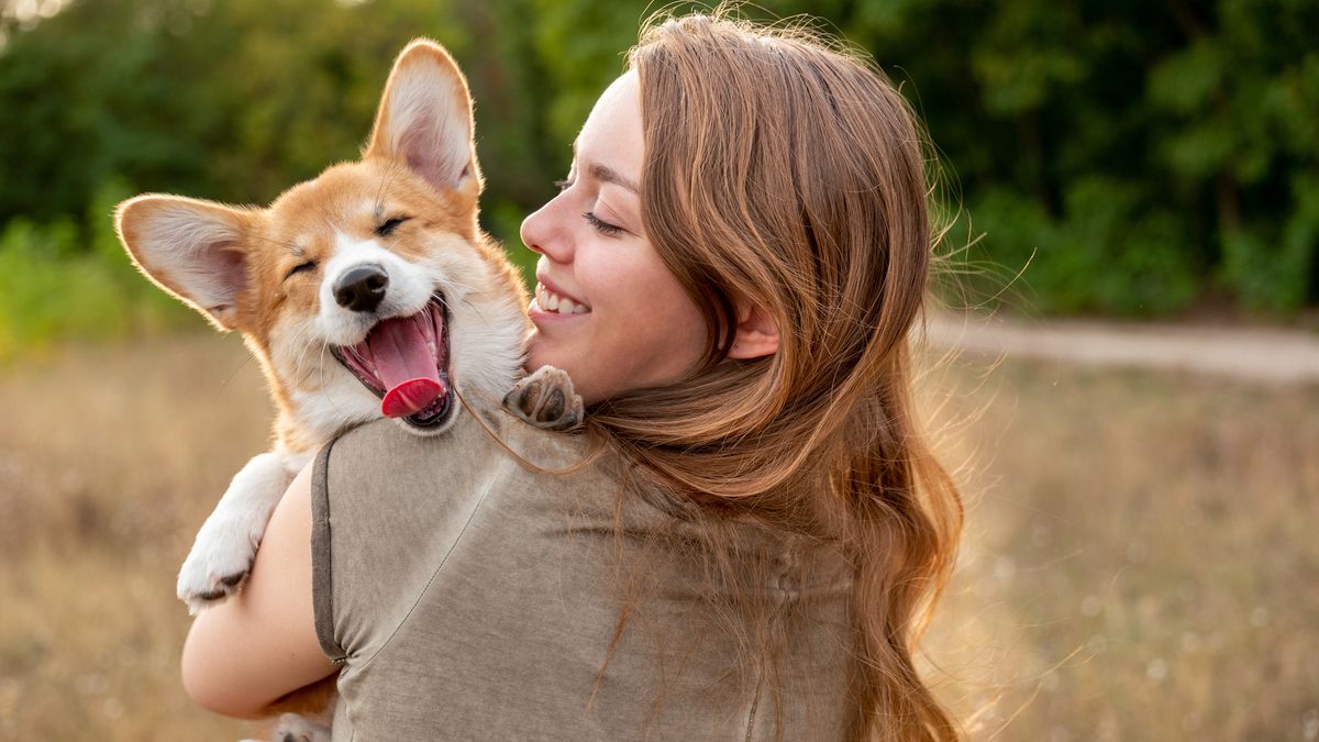 girl carrying corgi, smiling