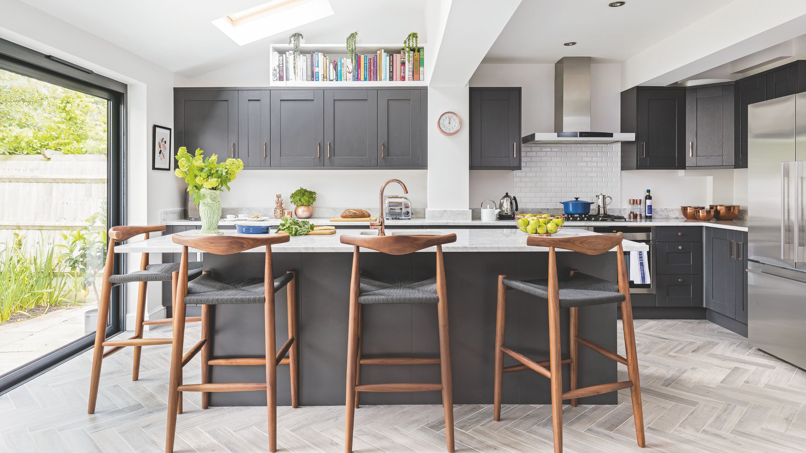 Large kitchen with island and stools around it, with grey cabinets