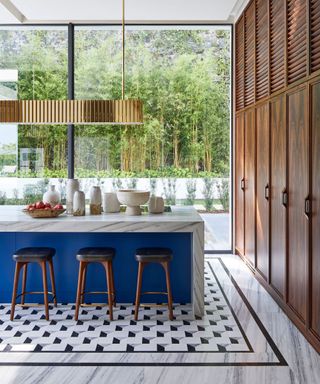 Humbert & Poyet kitchen with a blue and marble island and wooden floor to ceiling cabinets ©Francis Amiand