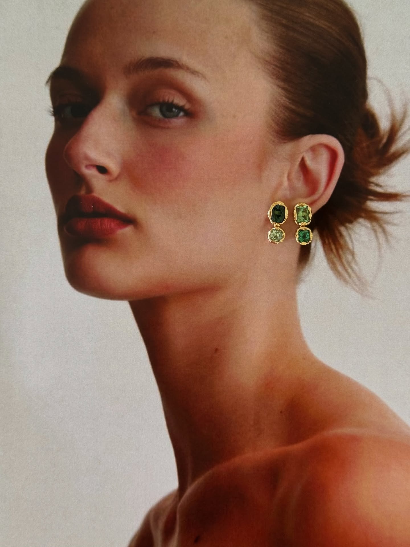 A model wearing emerald earrings.