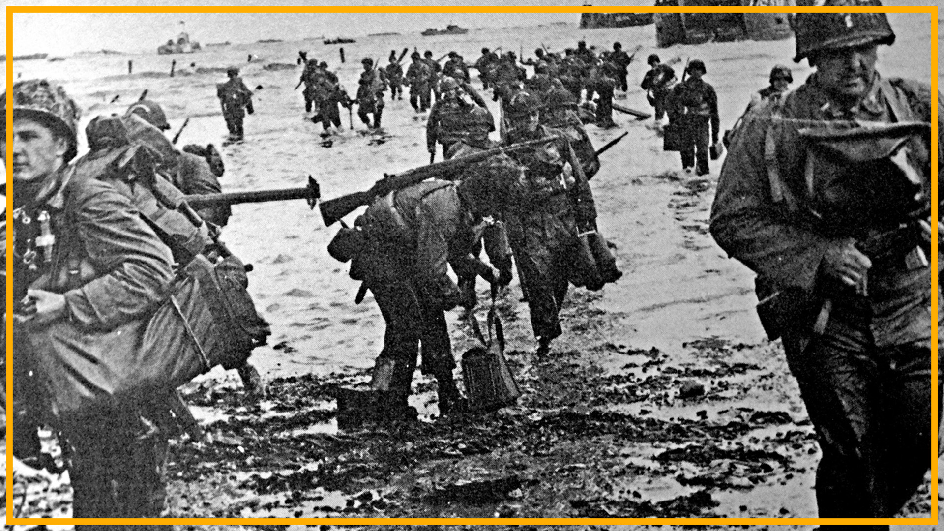 A black and white photo of soldiers in World War II uniforms walking up a beach. 