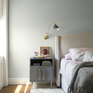 bedroom with white wall and wooden floor and bedside table