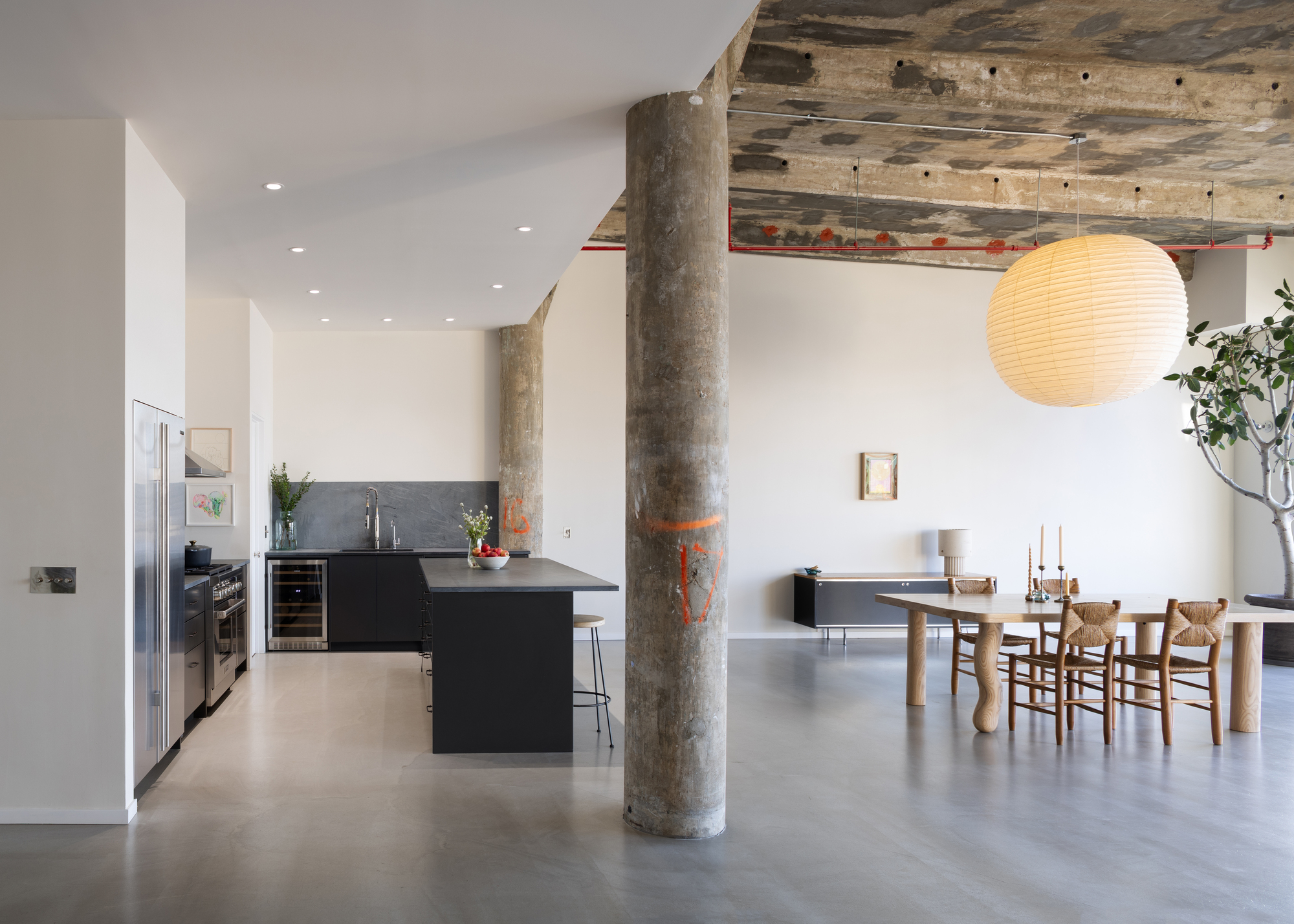 An open plan living area with concrete columns and minimalist furniture