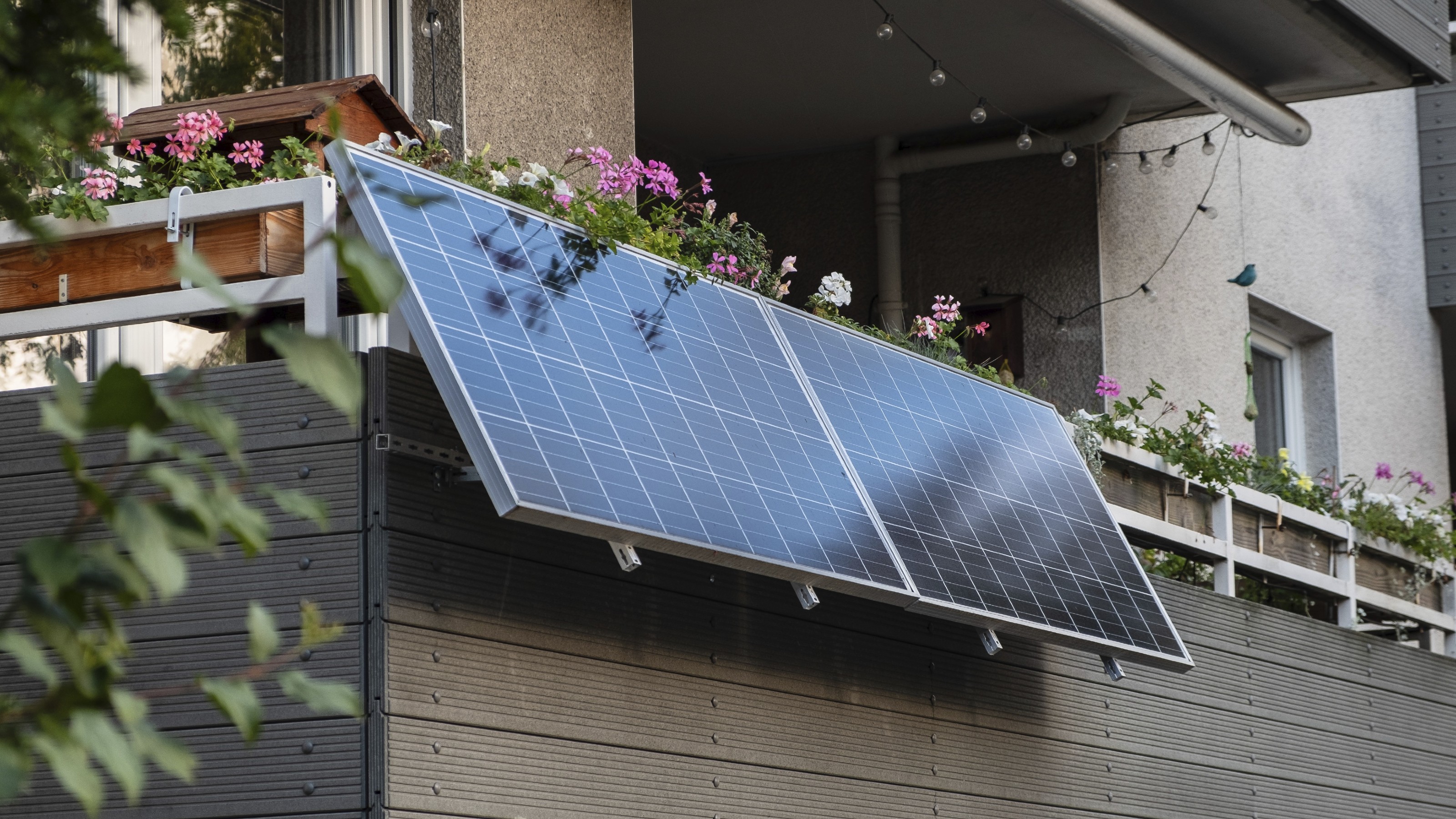 Angled solar panels installed on a balcony with flowers and festoon lights in Dusseldorf, Germany