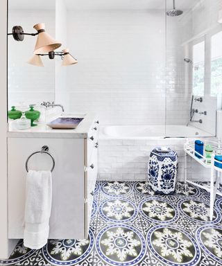 A master bathroom with a white tiled fitted bath and Mediterranean-style patterned floor tiles