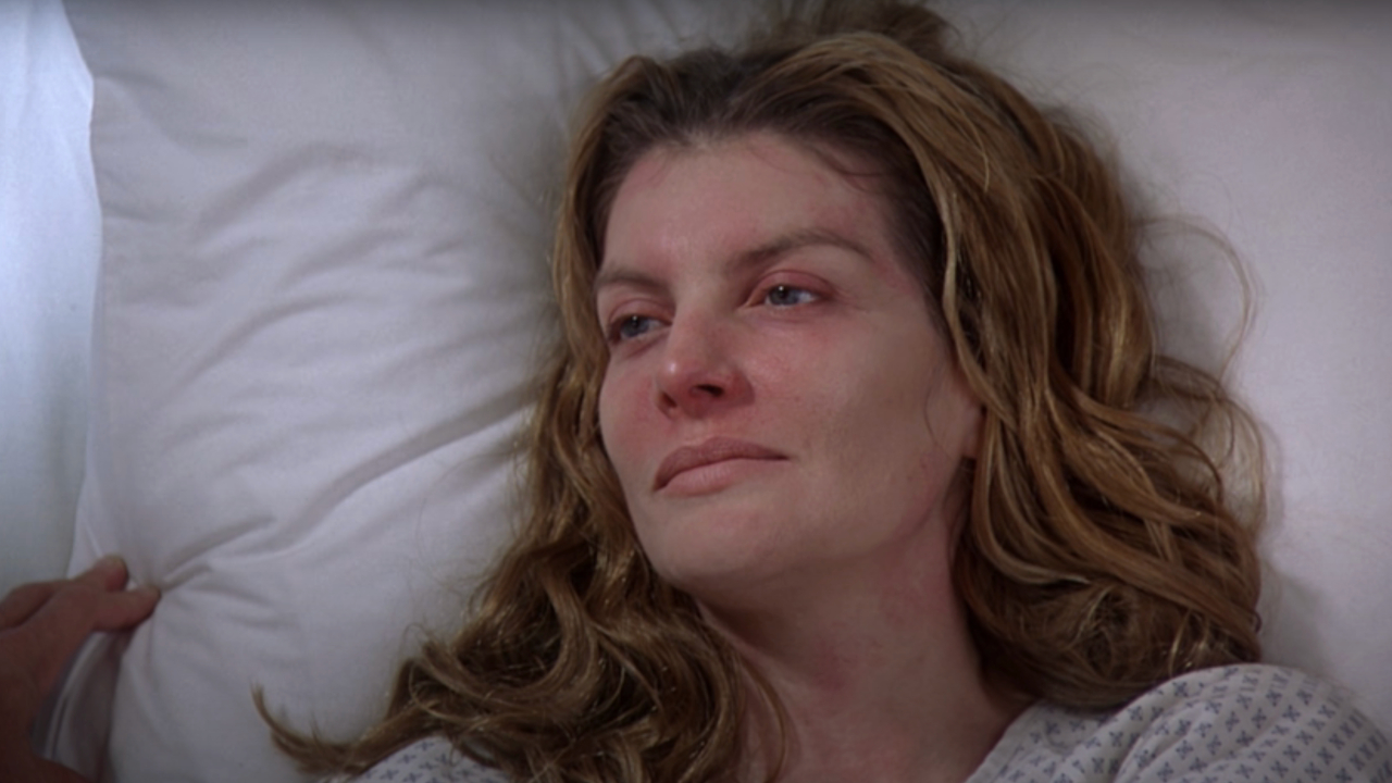 Rene Russo smiles as she lies recovering in a hospital bed in Outbreak.