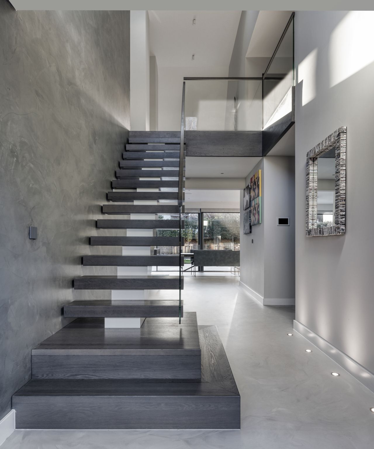 grey floating staircase in double height entrance hall with grey marble walls and floor