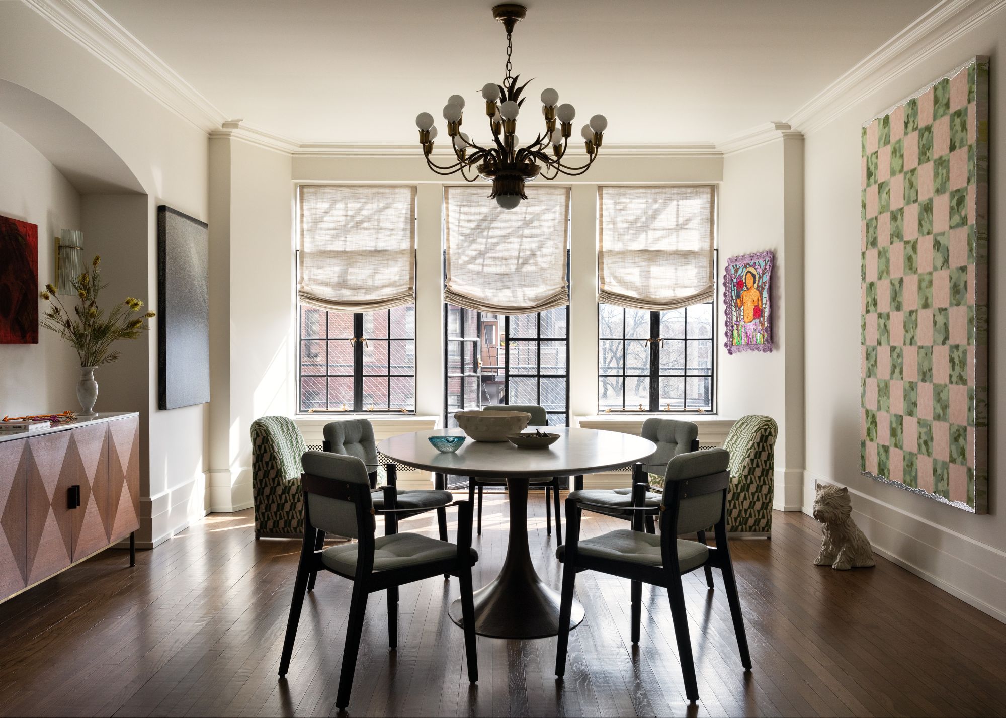 A modern dining room with French doors with neutral Roman blinds, wooden floors, and a dining table and chairs.