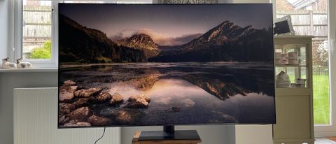 Samsung S95C OLED TV on stand with image of mountains on screen