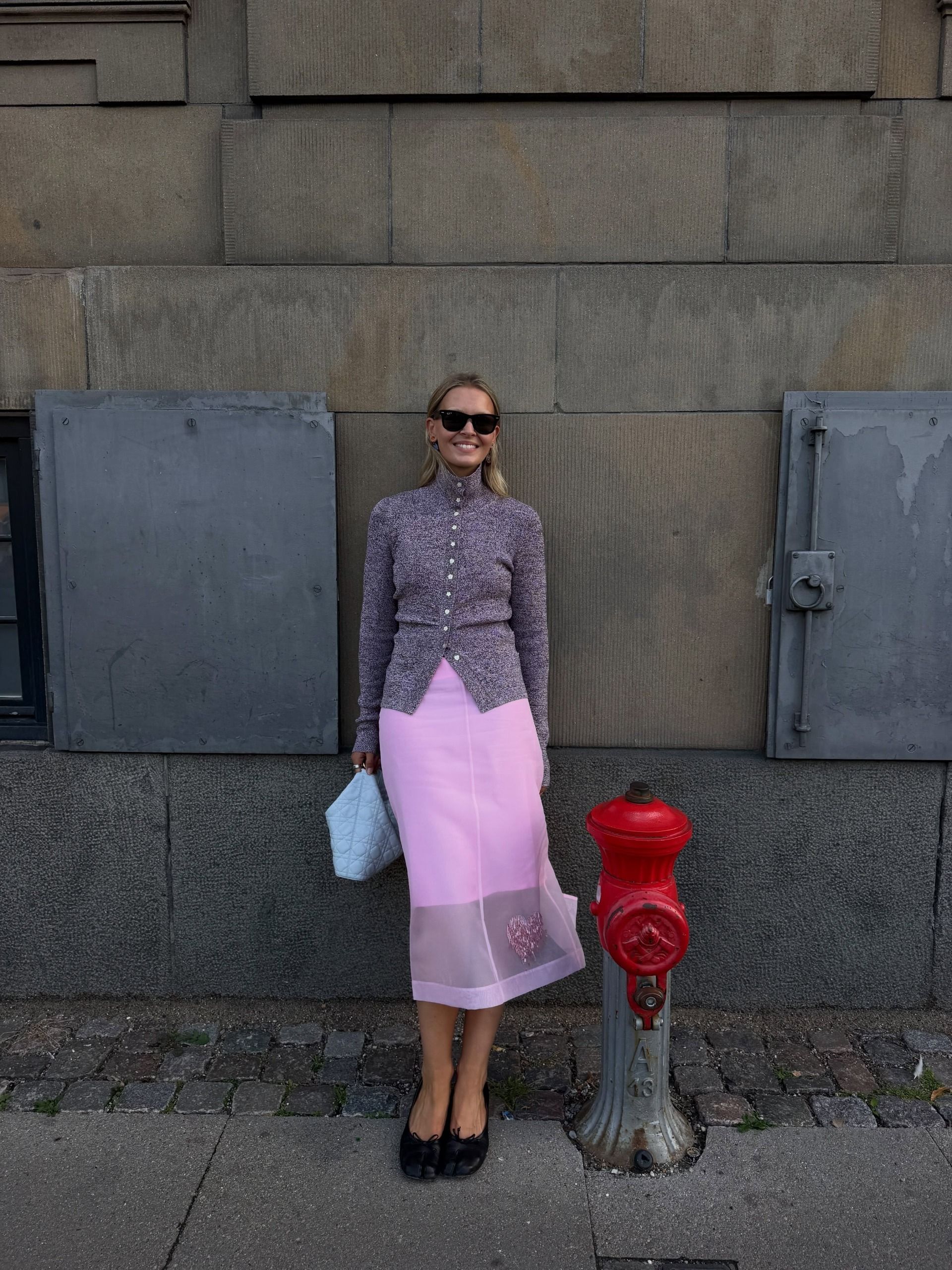 Influencer Hollie Mercedes wearing a turtleneck cardigan with pink sheer skirt.