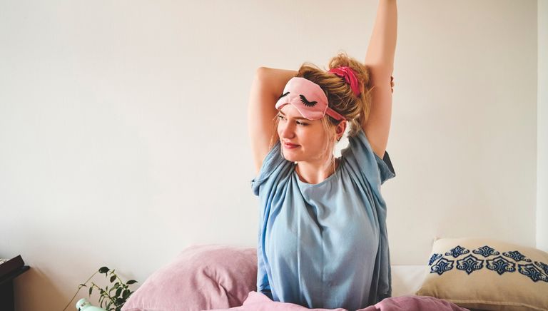 Cropped shot of an attractive young woman sitting in bed and stretching after waking up in the morning, best sleep aid, sleep accessories, sleep gadgets