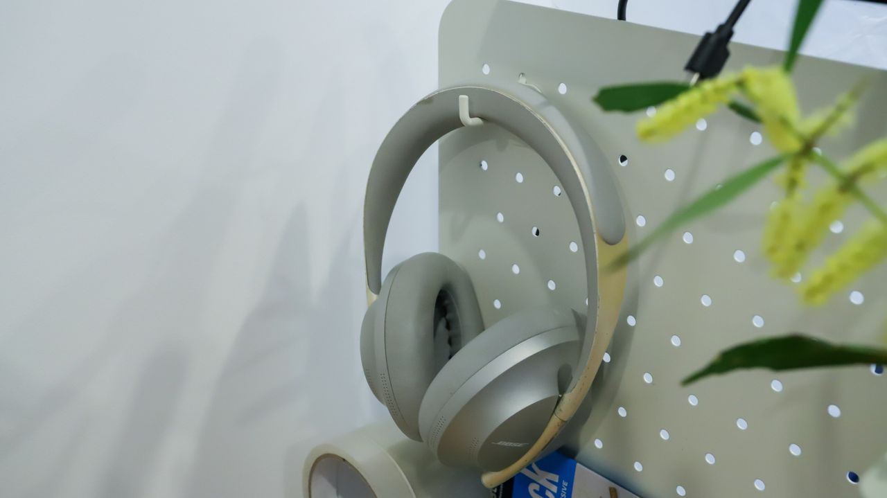 Over-ear headphones hanging from a hook of the EverDesk Max pegboard